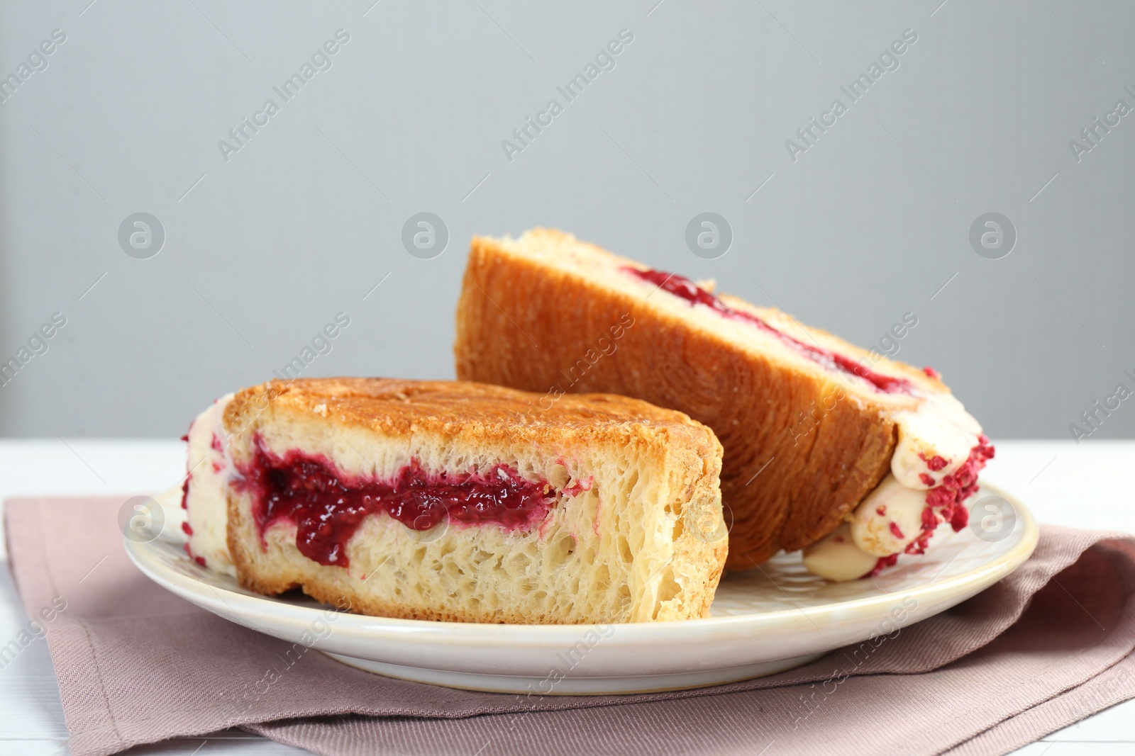 Photo of Round croissant with jam on table, closeup. Tasty puff pastry