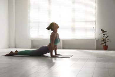 Photo of Woman practicing cobra asana in yoga studio. Bhujangasana pose