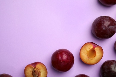 Photo of Delicious ripe plums on violet background, flat lay. Space for text