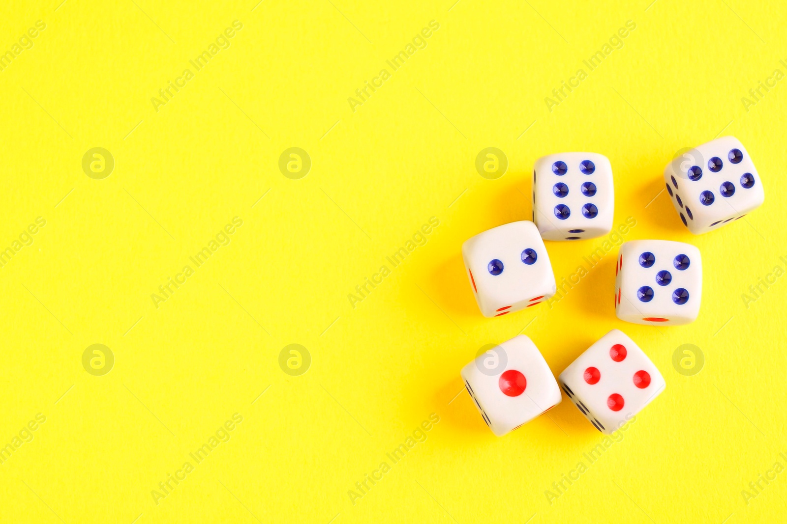 Photo of Many white game dices on yellow background, flat lay. Space for text