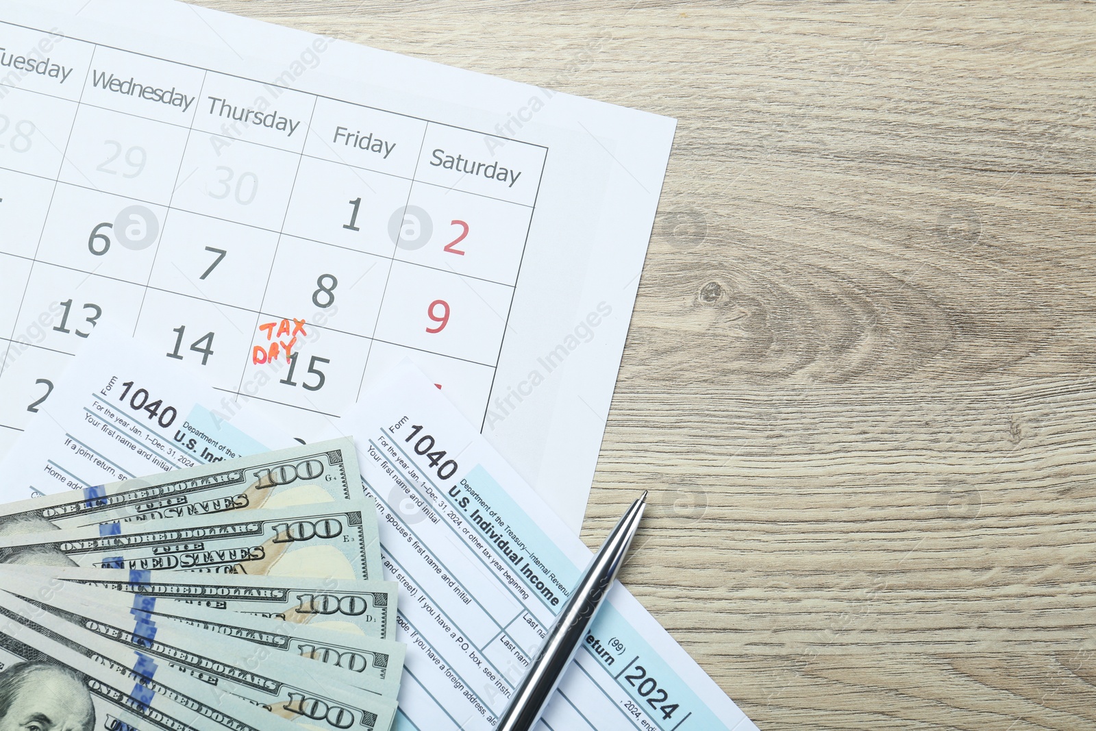 Photo of Tax day. Calendar with date reminder, documents, pen and dollar banknotes on wooden table, flat lay. Space for text