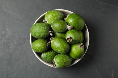 Fresh green feijoa fruits in bowl on black table, top view