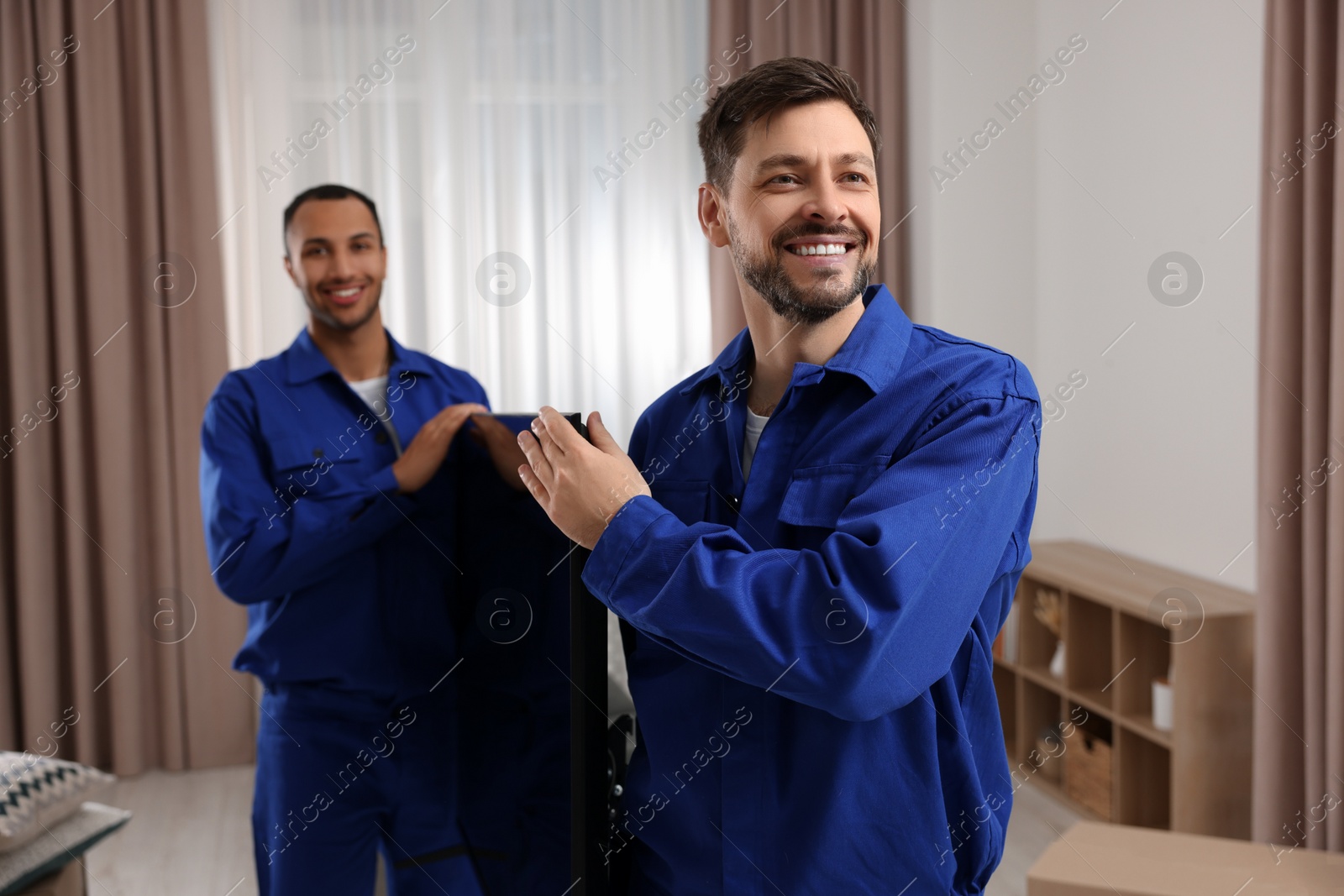 Photo of Male movers carrying plasma TV in new house