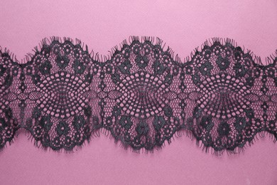 Black lace on purple background, top view