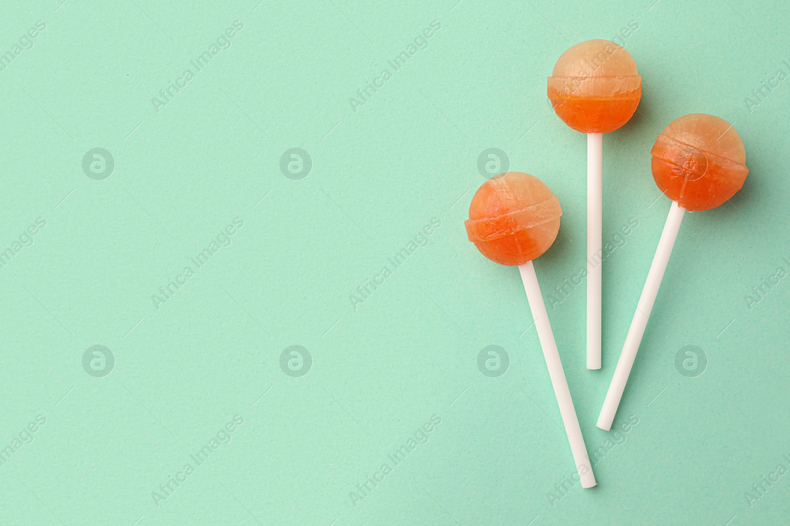 Photo of Tasty lollipops on turquoise background, flat lay. Space for text