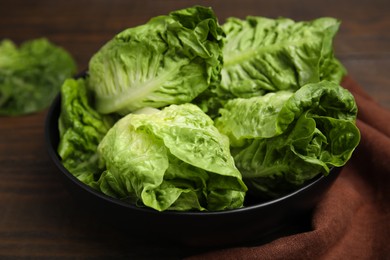 Photo of Bowl of fresh green romaine lettuces on wooden table, closeup