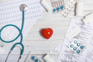 Flat lay composition with stethoscope and pills on wooden background. Cardiology service