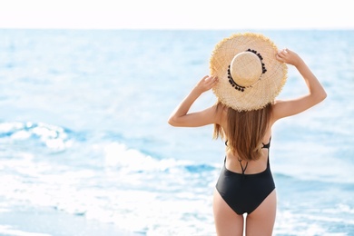 Photo of Attractive young woman in beautiful one-piece swimsuit on beach