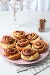 Many tasty cinnamon rolls on white table