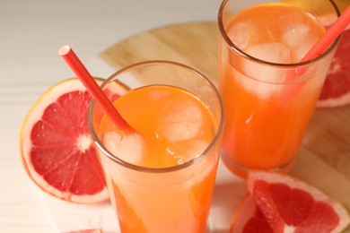 Photo of Tasty freshly made grapefruit juice and fruits on table, closeup