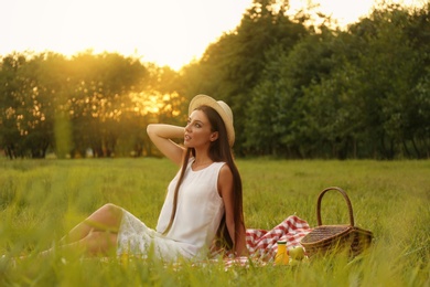 Photo of Young woman sitting on picnic blanket in park