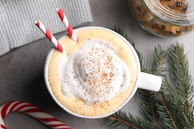 Cup of delicious eggnog with cinnamon on gray table, flat lay