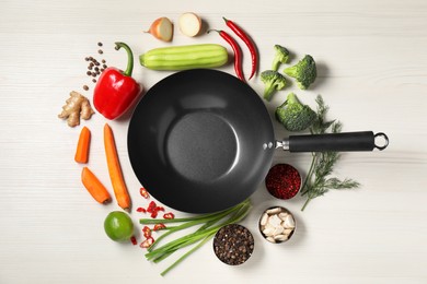 Photo of Empty iron wok surrounded by raw ingredients on white wooden table, flat lay