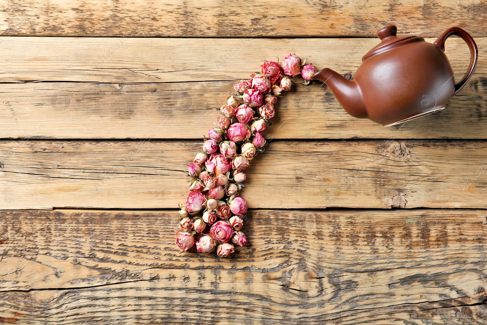 Photo of Flat lay composition with teapot and dried roses on wooden background