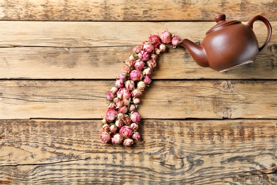 Photo of Flat lay composition with teapot and dried roses on wooden background