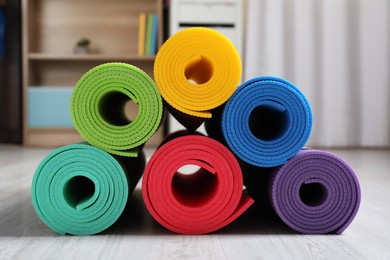 Photo of Bright rolled camping mats on white wooden floor indoors