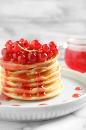 Delicious pancakes with fresh berries and syrup on marble table