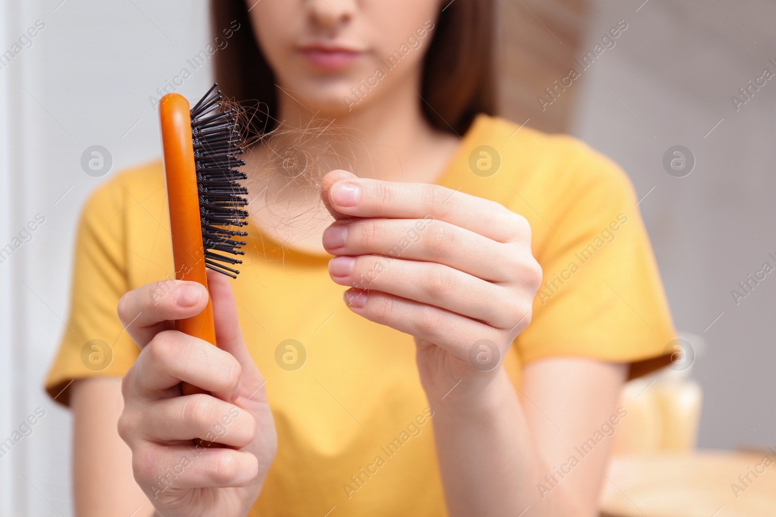 Photo of Young woman with brush indoors, closeup. Hair loss problem