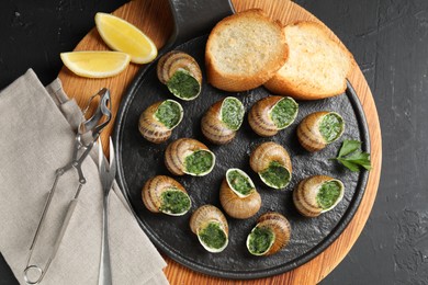 Delicious cooked snails served on grey textured table, flat lay