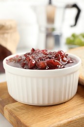 Delicious gooseberry jam in bowl on wooden board, closeup
