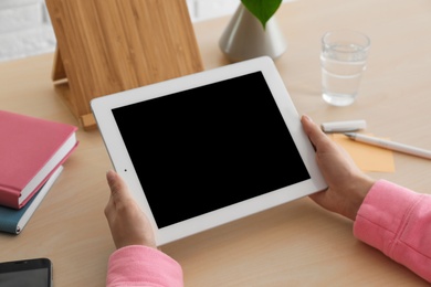 Photo of Woman using tablet at table, closeup. Space for design