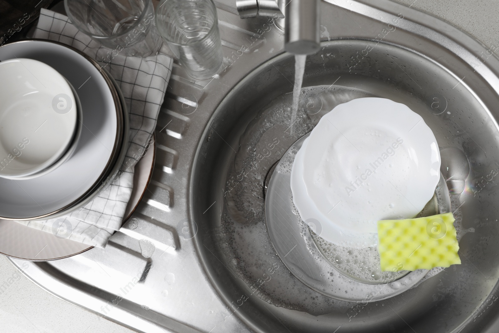 Photo of Washing plates in kitchen sink, above view