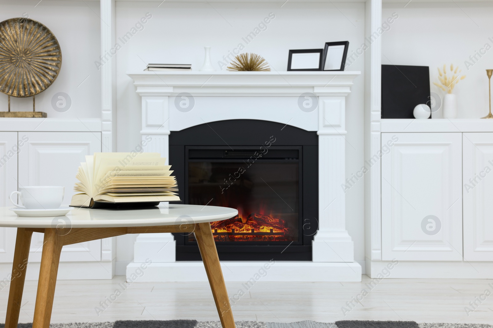 Photo of Stylish room with beautiful fireplace and book on table. Interior design