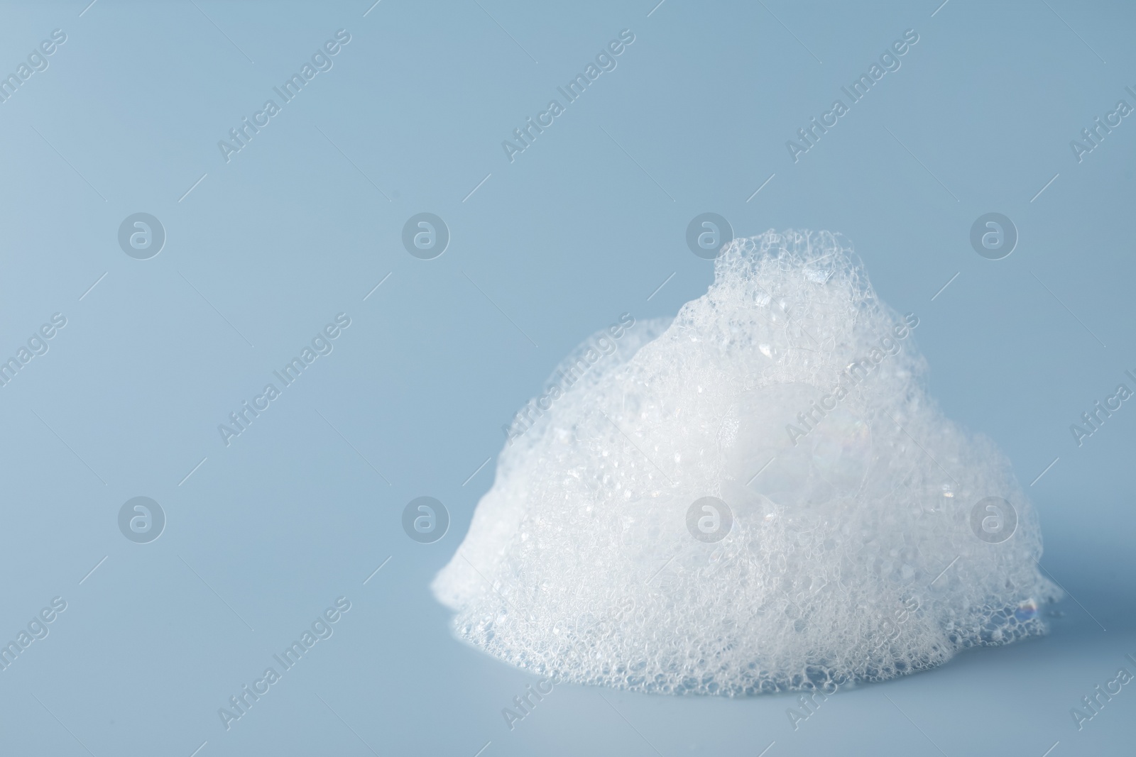 Photo of Drop of fluffy bath foam on light blue background. Space for text