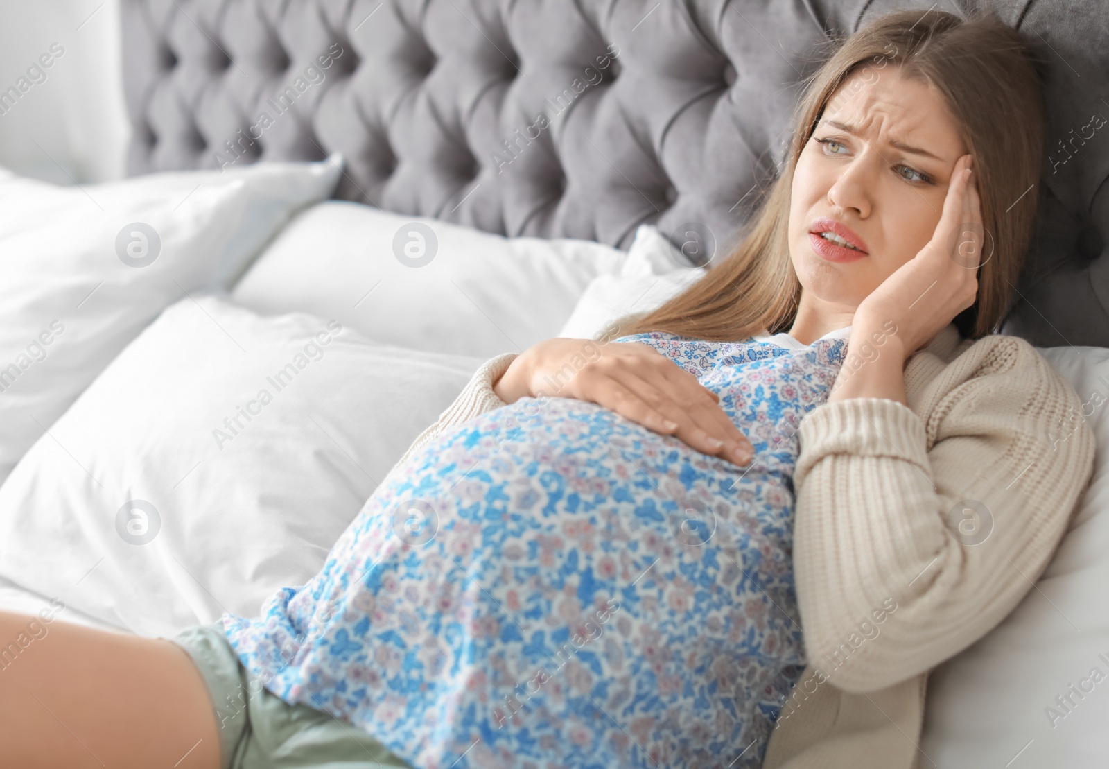 Photo of Young pregnant woman suffering from headache at home