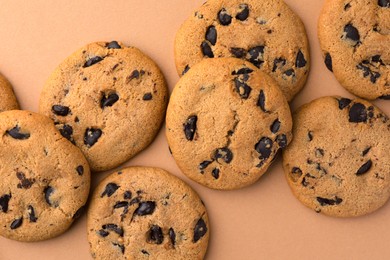 Photo of Many delicious chocolate chip cookies on beige background, flat lay