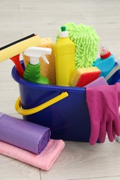 Different cleaning supplies in bucket on floor