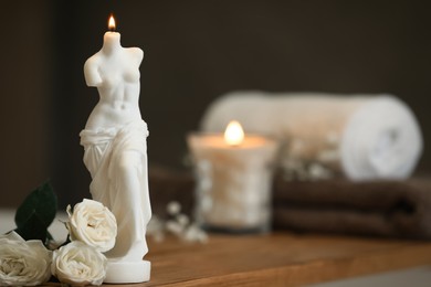 Beautiful Venus De Milo candle and white roses on wooden table in room, space for text