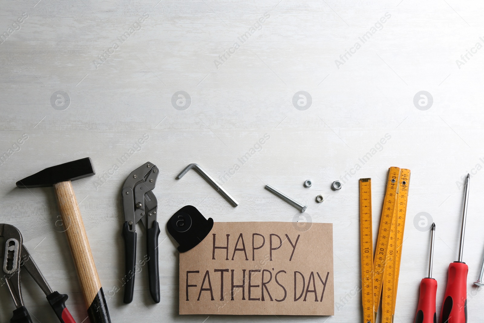 Photo of Card with words HAPPY FATHER'S DAY and tools on white background, flat lay. Space for text