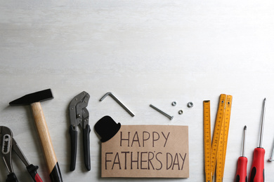Photo of Card with words HAPPY FATHER'S DAY and tools on white background, flat lay. Space for text