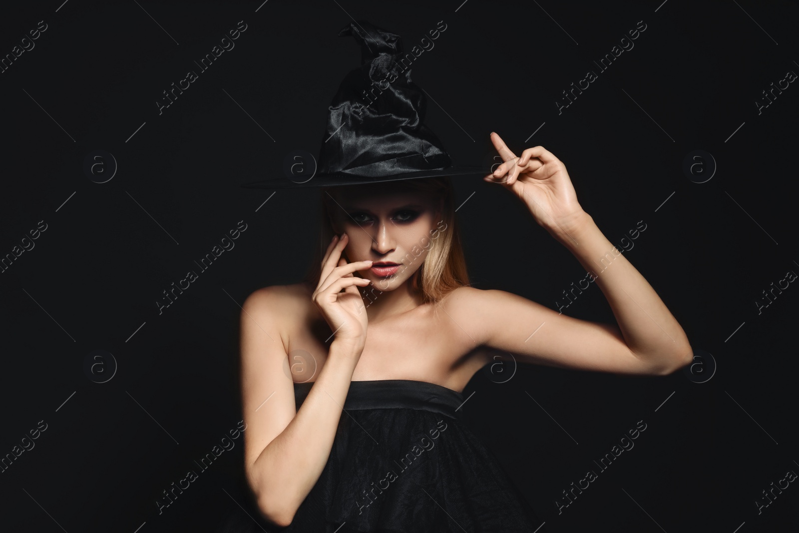 Photo of Witch in black hat on dark background. Scary fantasy character