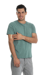 Happy man with sticking plaster on arm against white background