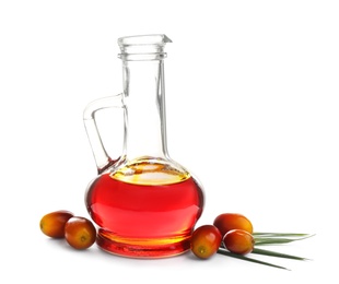 Photo of Palm oil in glass jug, tropical leaf and fruits isolated on white