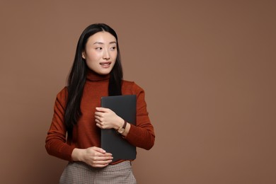 Photo of Portrait of smiling woman with laptop on brown background. Space for text