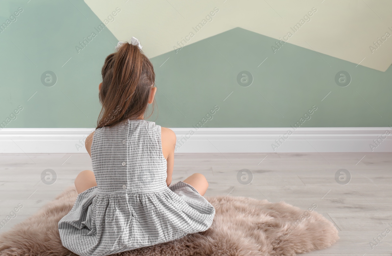Photo of Lonely little girl sitting on floor indoors. Child autism