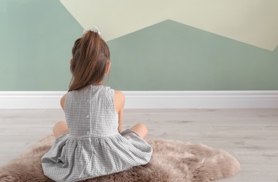 Lonely little girl sitting on floor indoors. Child autism