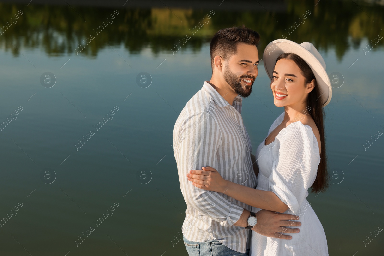 Photo of Romantic date. Beautiful couple spending time together near lake, space for text