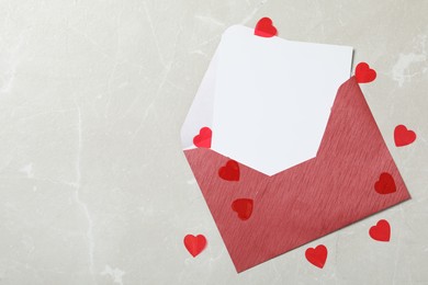 Photo of Blank card, envelope and red hearts on light background, flat lay with space for text. Valentine's Day celebration