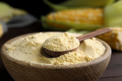 Corn flour and spoon in bowl, closeup view