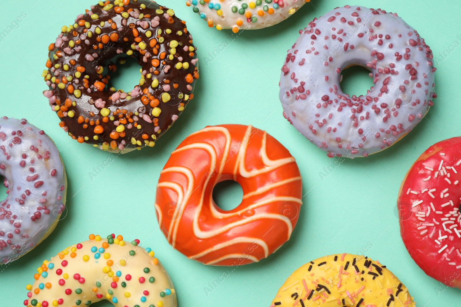 Photo of Delicious glazed donuts on turquoise background, flat lay