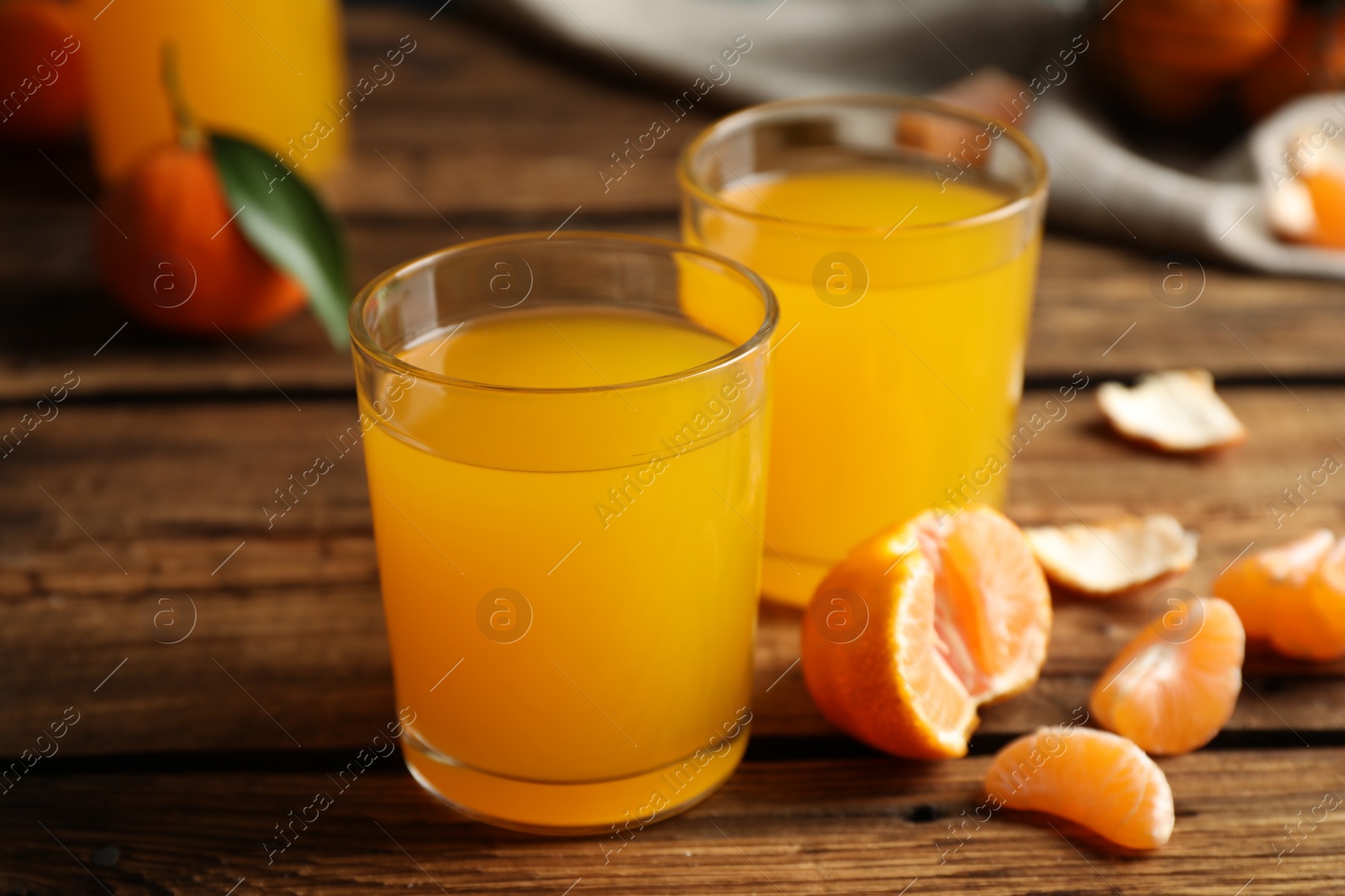 Photo of Glasses of fresh tangerine juice and fruits on wooden table