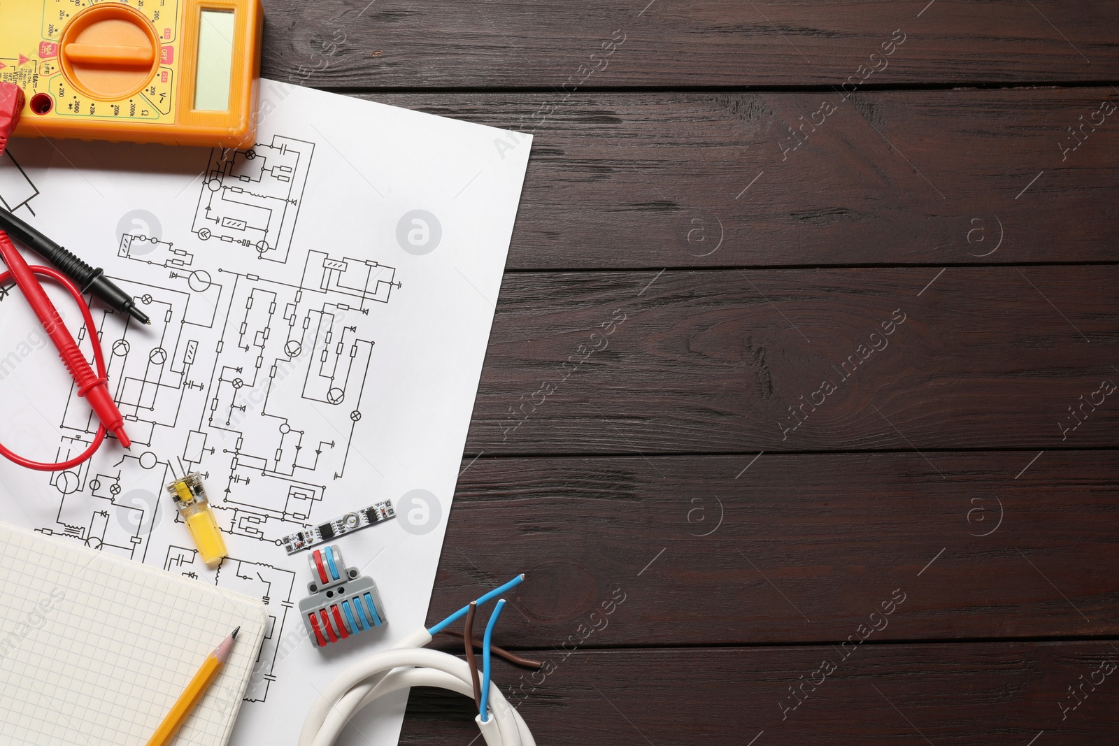 Photo of Wiring diagram, office stationery, wires and digital multimeter on wooden table, top view. Space for text