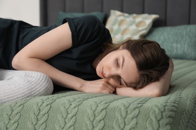 Photo of Sad young woman lying on bed at home