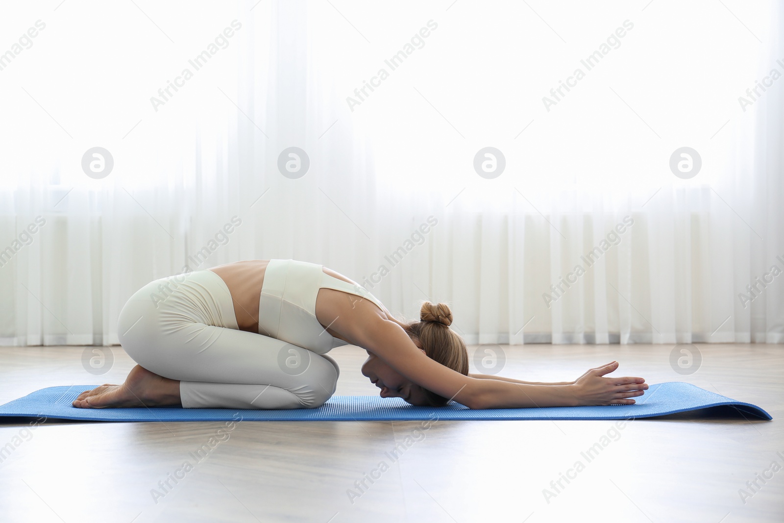 Photo of Young woman practicing extended child asana in yoga studio. Utthita Balasana pose