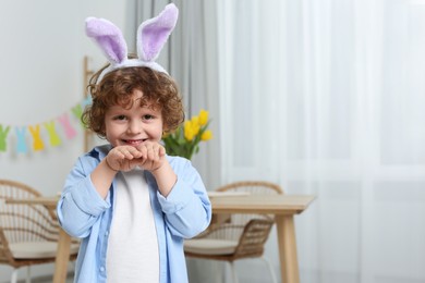 Easter celebration. Happy boy wearing cute bunny ears headband at home. Space for text