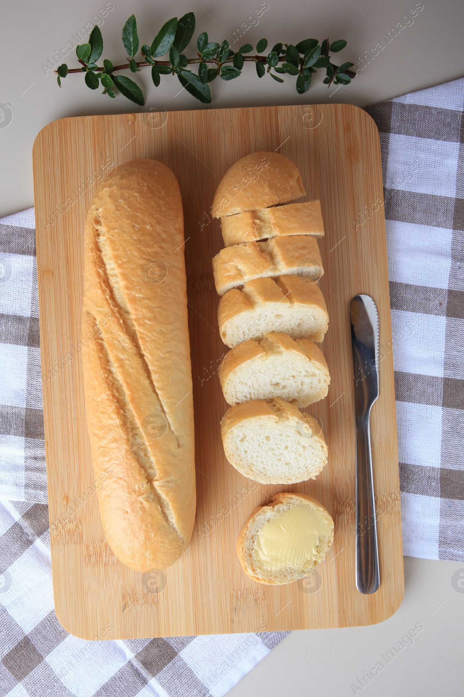 Photo of Whole and cut baguettes with fresh butter on table, flat lay